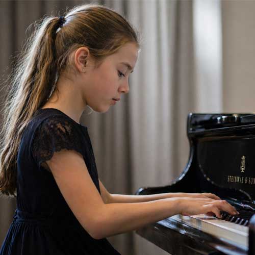Jeune élève jouant du piano en se concentrant sur son geste technique lors d’une masterclass