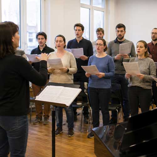 Chanteurs et chanteuses répétant ensemble sous la direction d’une cheffe de chœur